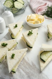 Photo of Tasty sandwiches with cucumber, butter and parsley on white marble table
