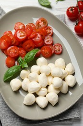 Delicious mozzarella balls, tomatoes and basil leaves on table, flat lay