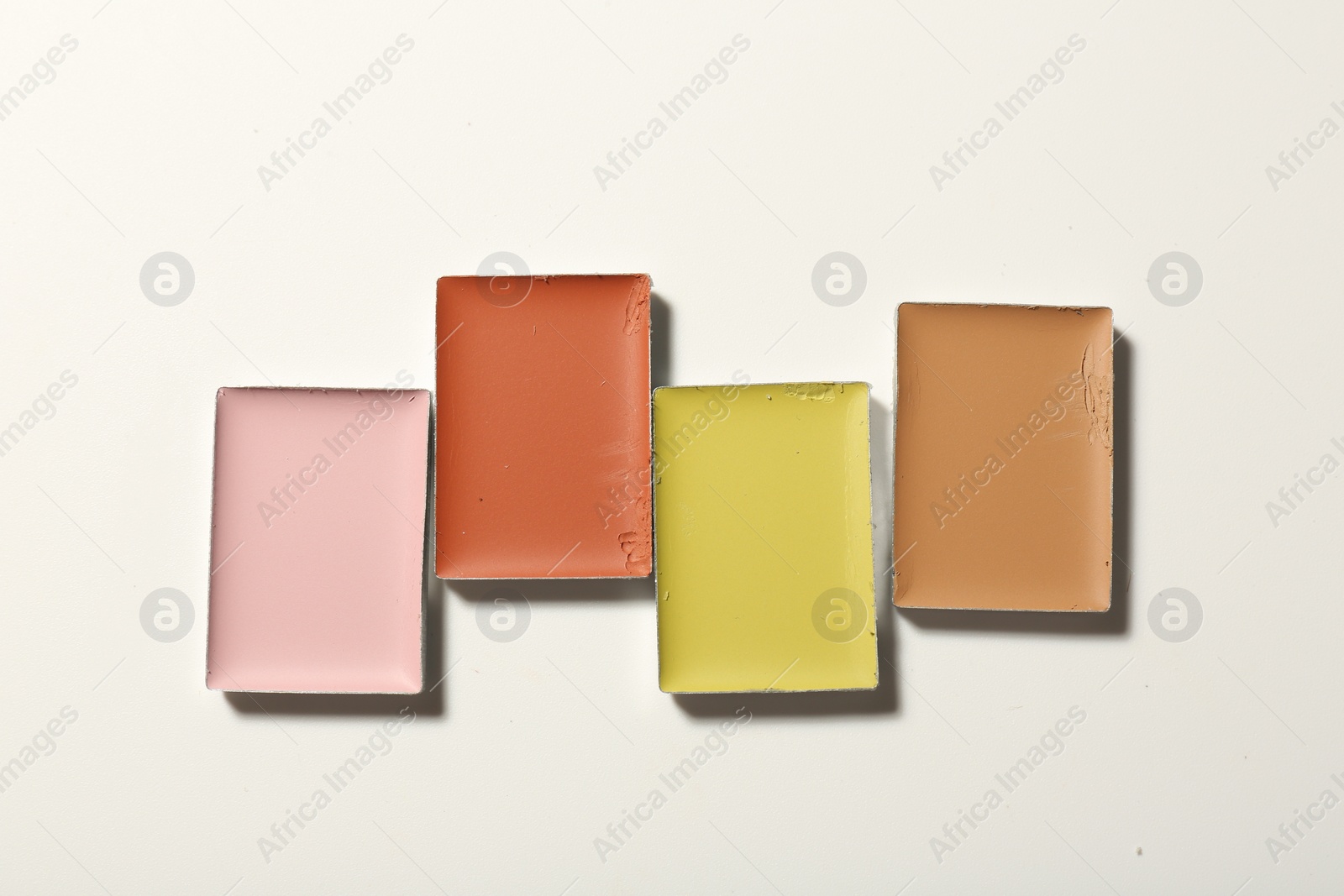 Photo of Different color correcting concealers on white background, top view