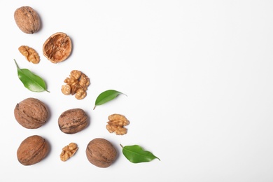 Walnuts with leaves on white background, flat lay with space for text