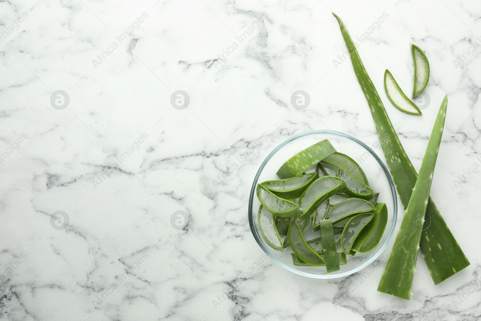 Photo of Fresh aloe vera pieces on white marble table, flat lay. Space for text