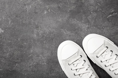 Photo of Pair of white sneakers on dark background, top view