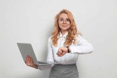 Emotional businesswoman with laptop in turmoil over being late on white background