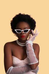 Photo of Fashionable portrait of beautiful woman with stylish sunglasses on beige background