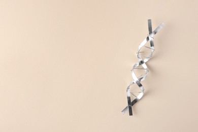 Photo of DNA molecular chain model made of metal on beige background, top view. Space for text