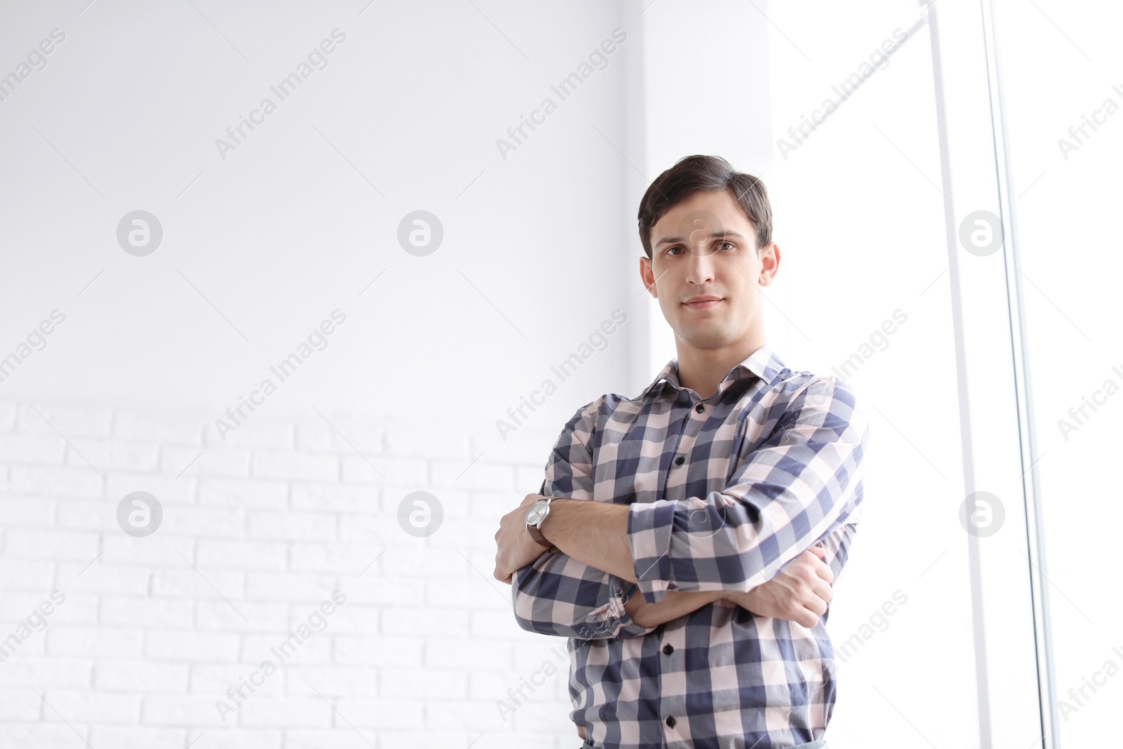 Photo of Portrait of confident young man near window, indoors