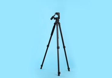 Photo of Modern tripod for camera on light blue background