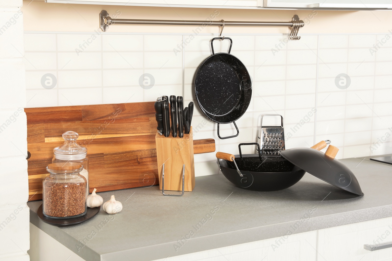 Photo of Set of clean cookware, utensils and products on table in modern kitchen