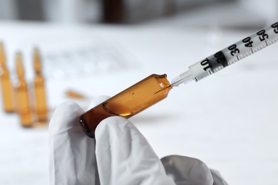 Photo of Doctor filling syringe with medication from pharmaceutical ampoule indoors, closeup