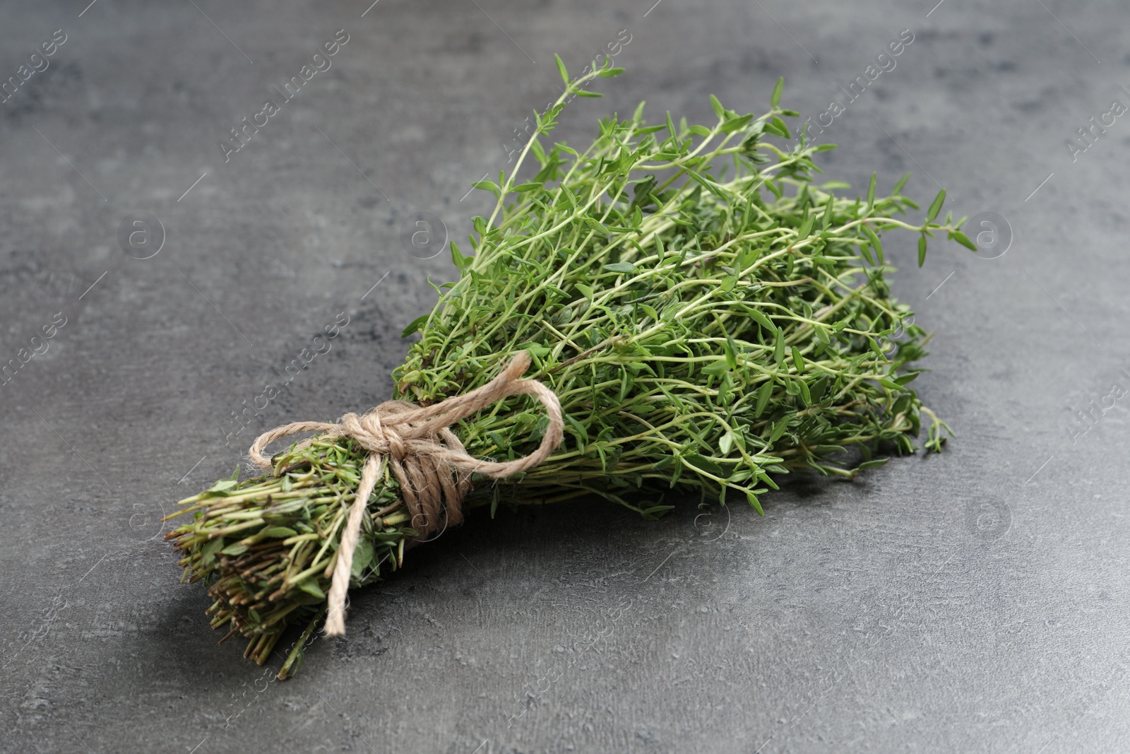 Photo of Bunch of aromatic thyme on grey table