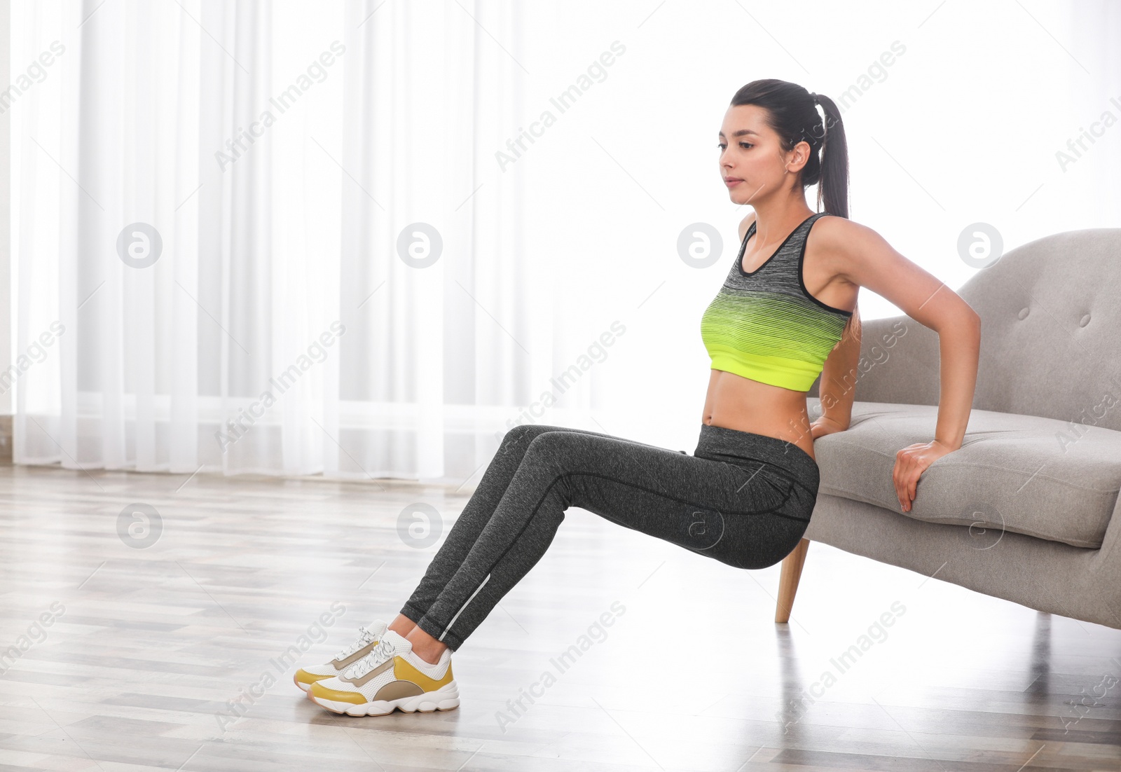 Photo of Young woman in fitness clothes doing exercise at home. Space for text