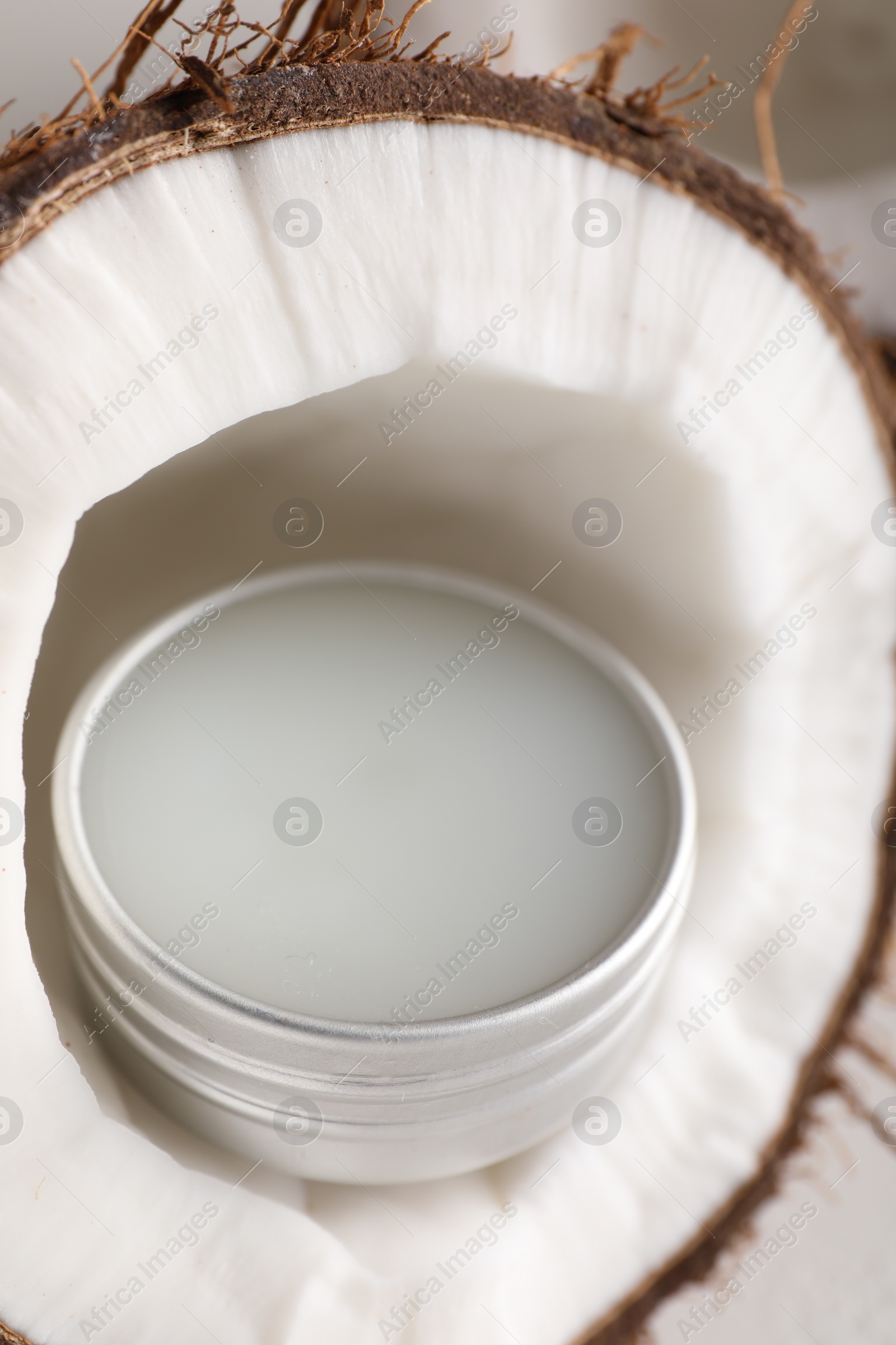 Photo of Lip balm inside coconut on light background, closeup