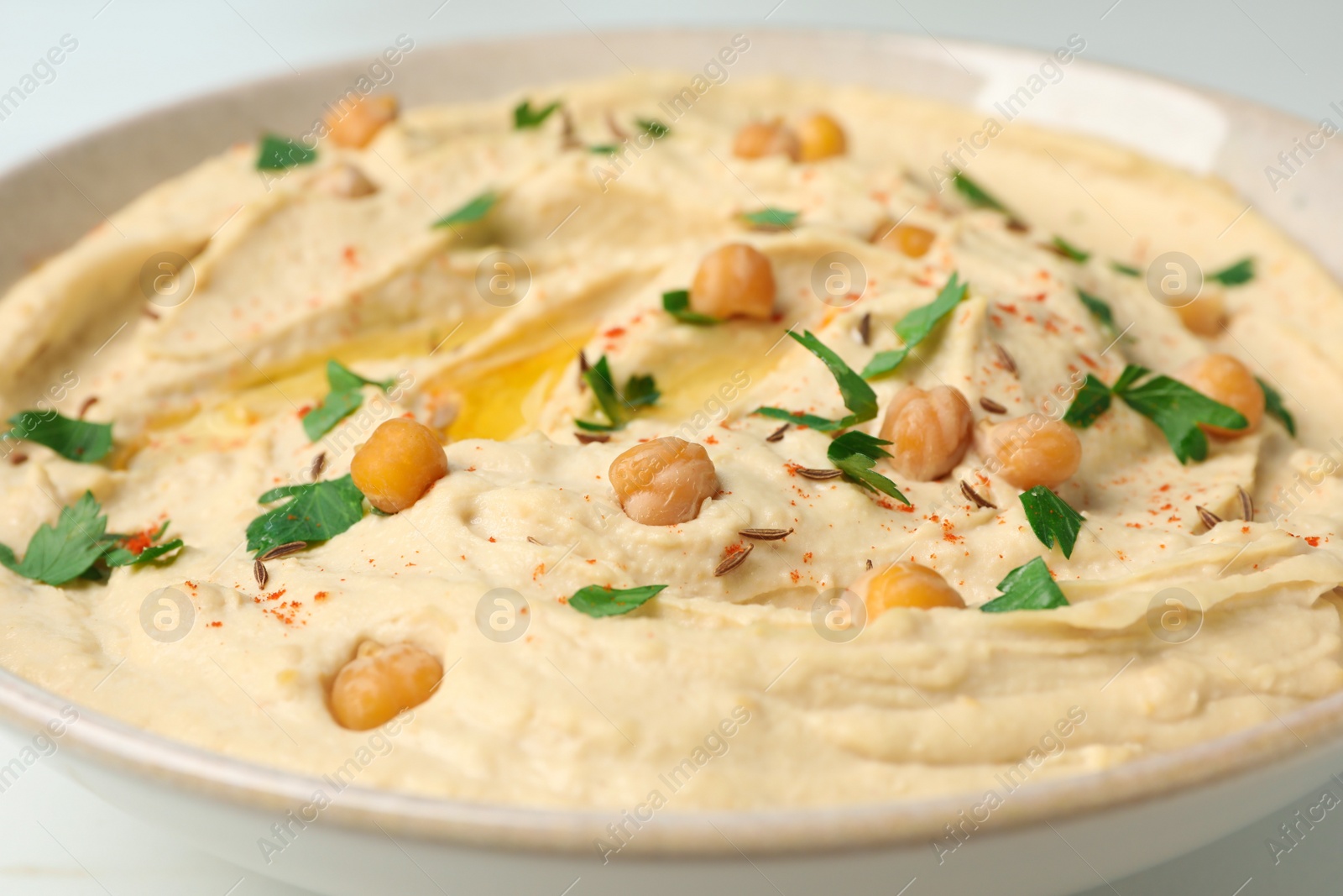 Tasty hummus with garnish in bowl, closeup Photo of Tasty hummus with garnish in bowl, closeup