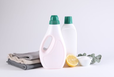 Bottles of cleaning product, brush, rags and lemon on light background