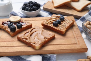 Photo of Different tasty toasts with nut butter and products on table, closeup
