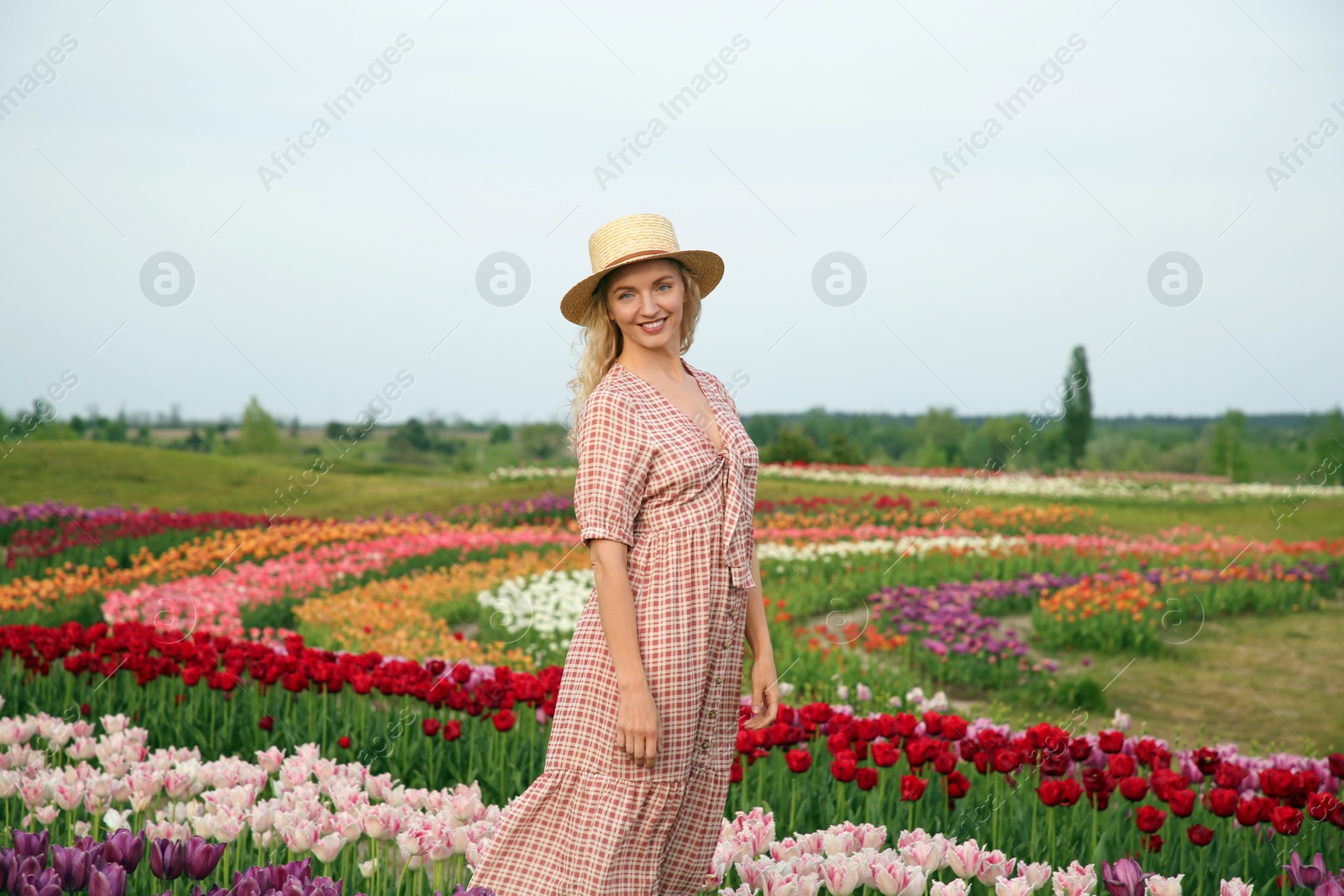 Photo of Happy woman in beautiful tulip field outdoors