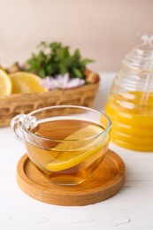 Photo of Cup of delicious tea with lemon and honey on white table