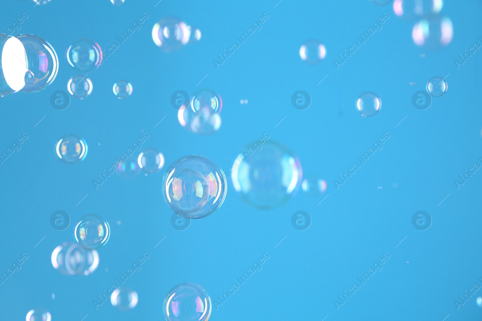 Photo of Beautiful transparent soap bubbles on light blue background