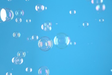 Beautiful transparent soap bubbles on light blue background