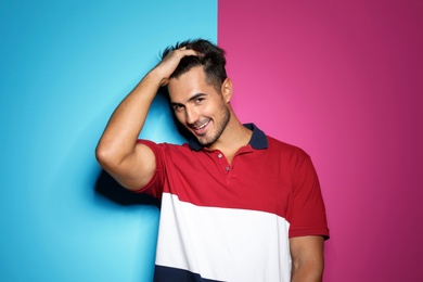 Young man with trendy hairstyle posing on color background