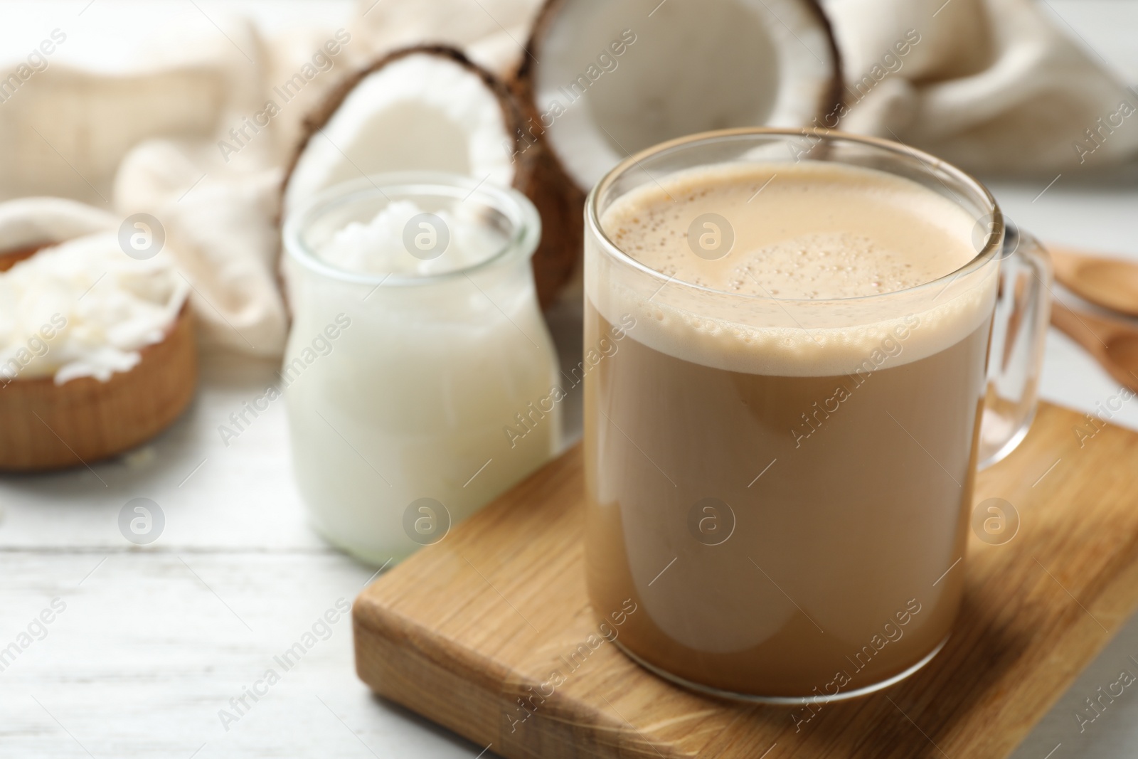 Photo of Delicious coffee with organic coconut oil on white wooden table