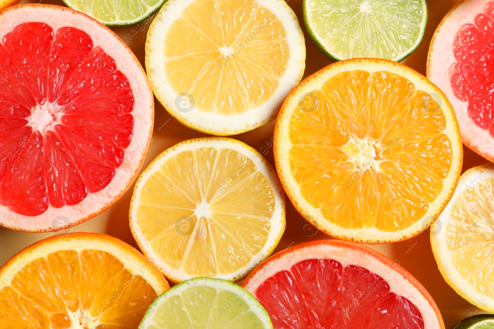 Photo of Different cut citrus fruits on beige table, flat lay