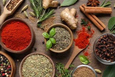 Photo of Different herbs and spices on wooden table, flat lay