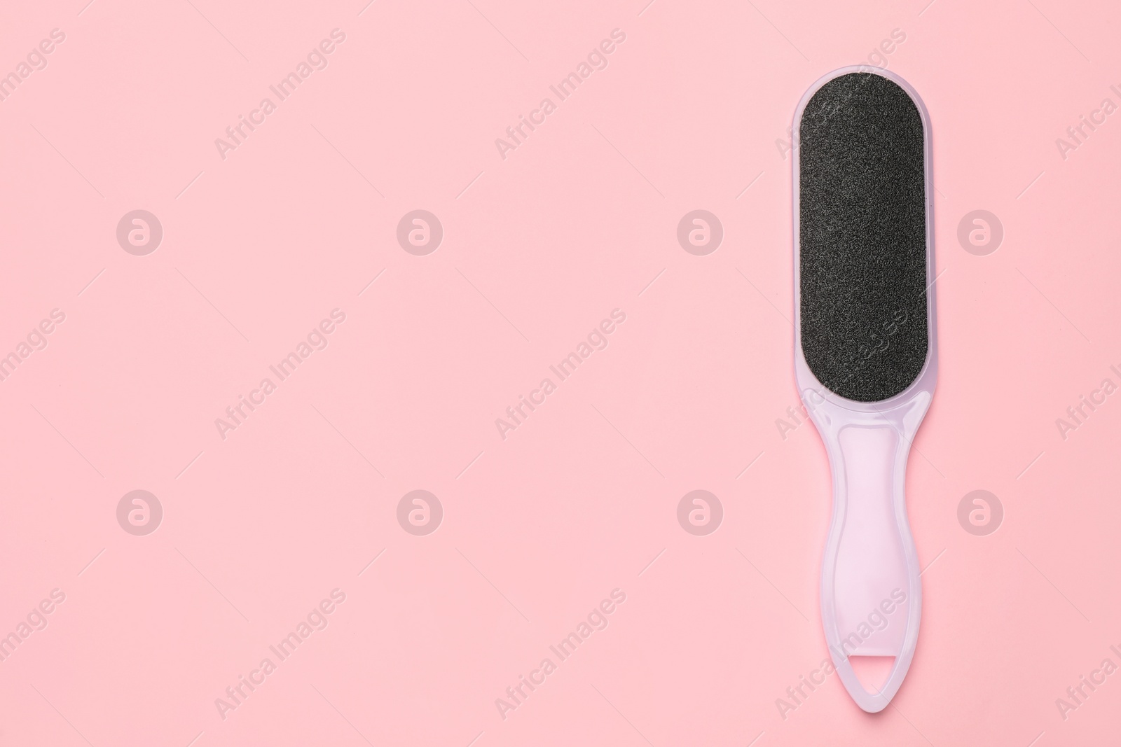 Photo of Foot file on pink background, top view with space for text. Pedicure tool