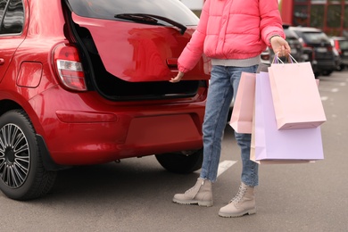 Photo of Woman with shopping bags near her car outdoors, closeup