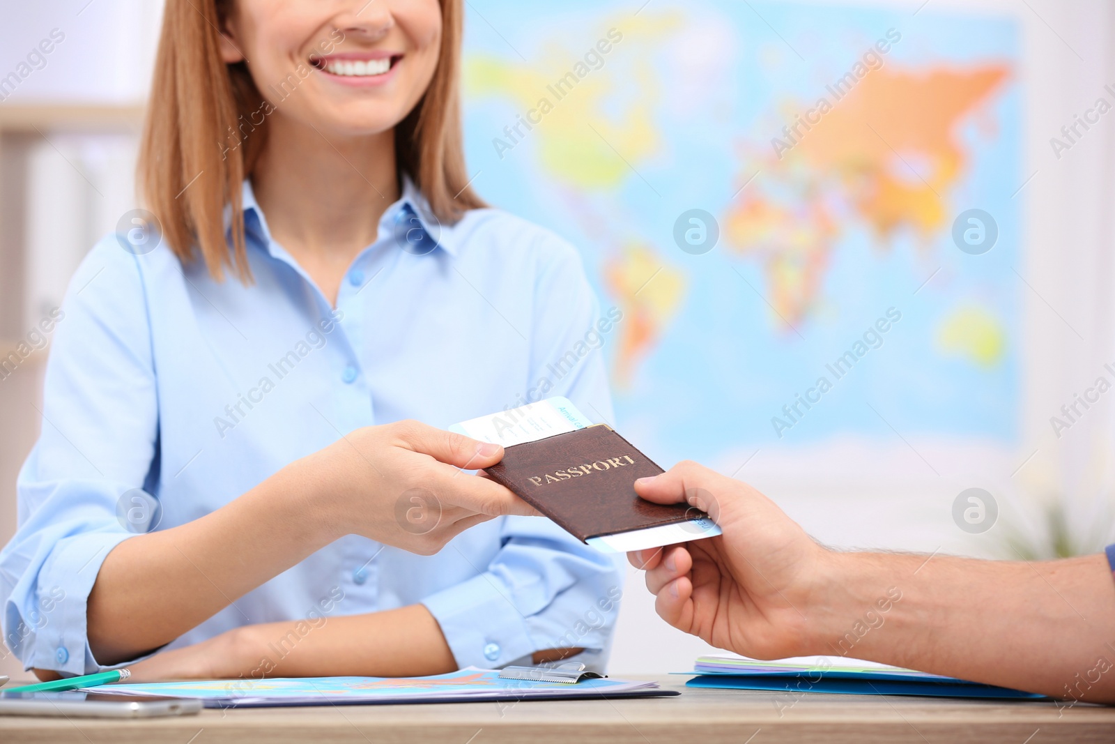 Photo of Female manager giving passport with ticket to client in travel agency