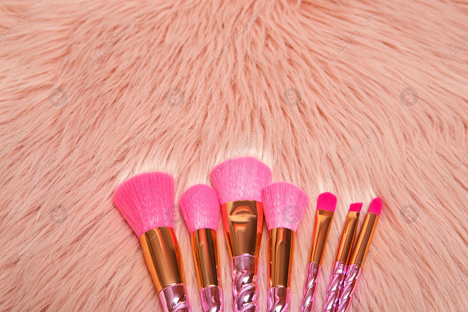 Photo of Set of professional makeup brushes on furry fabric, above view. Space for text