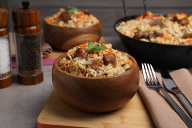 Delicious pilaf with meat and carrot in bowl on grey table, closeup