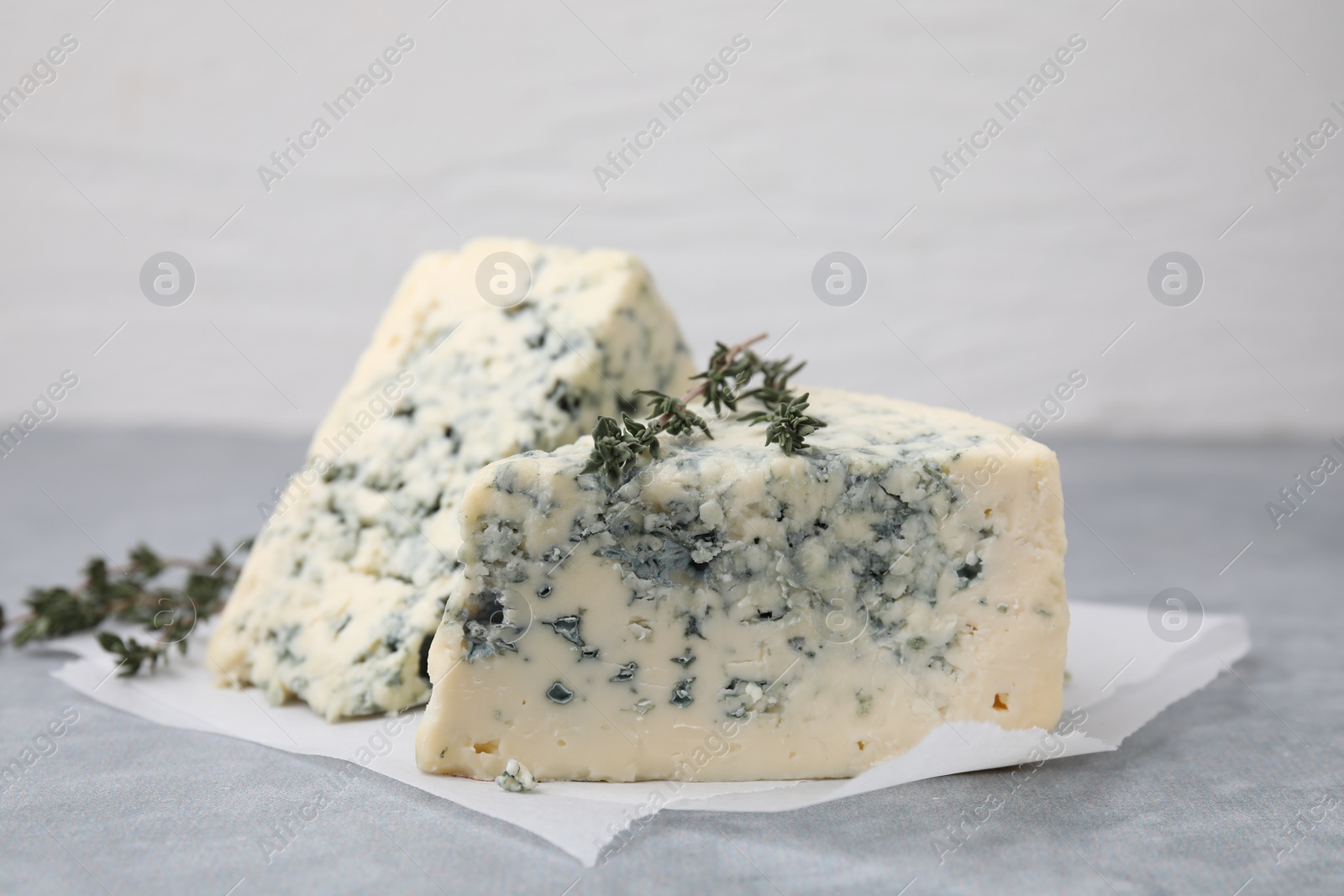 Photo of Tasty blue cheese with thyme on grey table