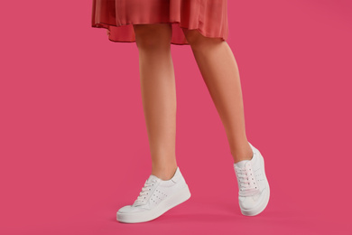 Woman wearing shoes on pink background, closeup