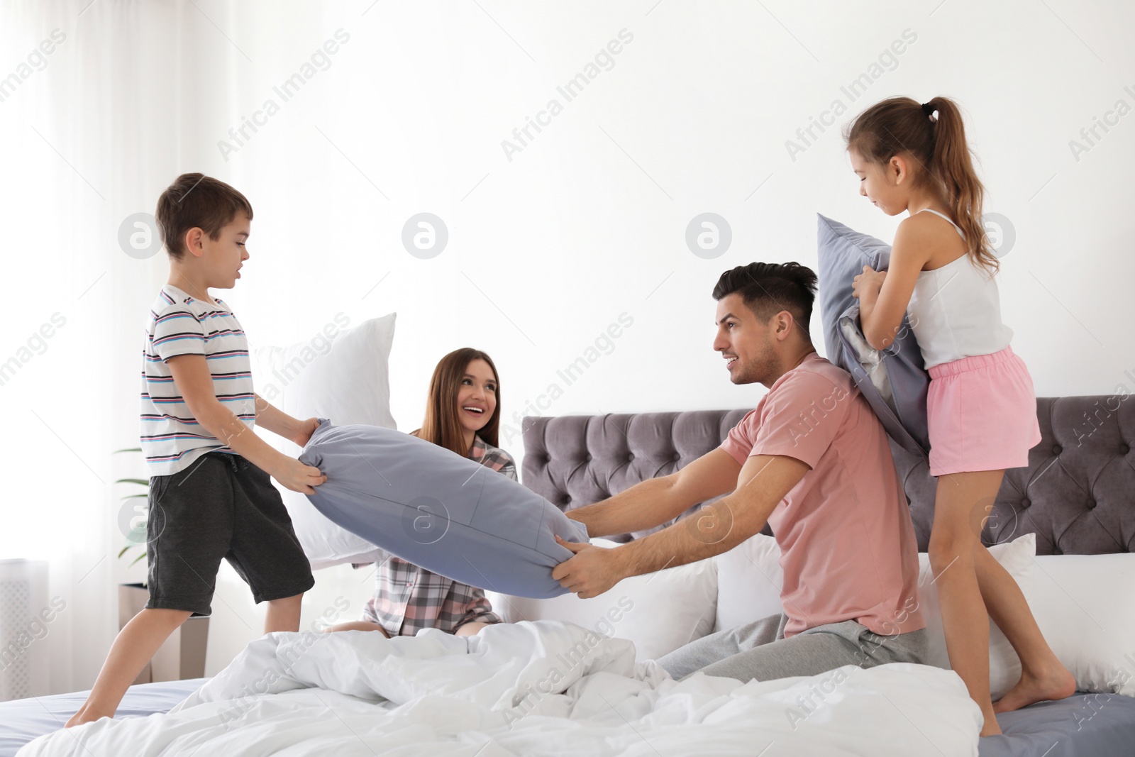 Photo of Happy family having pillow fight in bedroom