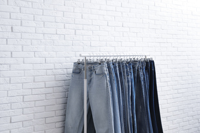 Photo of Rack with stylish jeans near brick wall