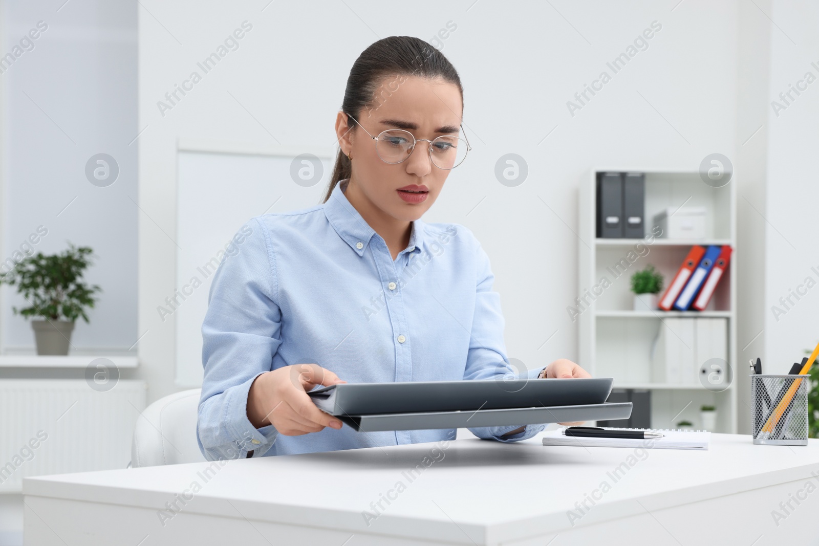 Photo of Unhappy young female intern at table in office