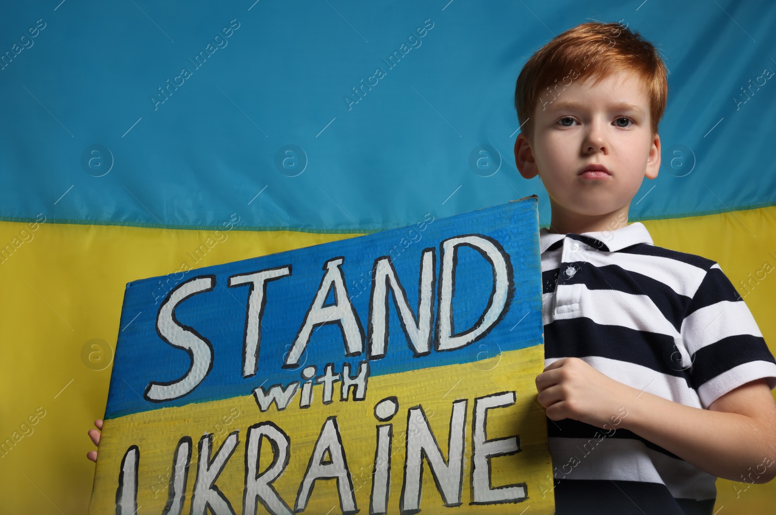 Photo of Boy holding poster Stand with Ukraine against national flag