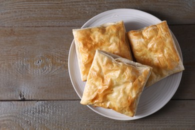 Delicious fresh puff pastries on wooden table, top view. Space for text