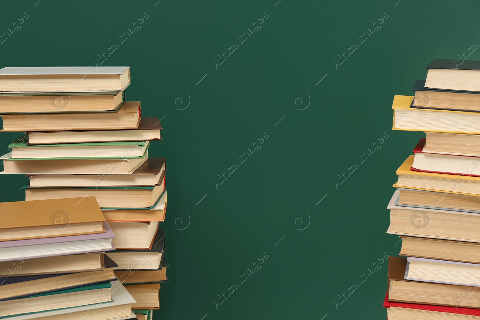 Photo of Many hardcover books near green chalkboard, space for text. Library material