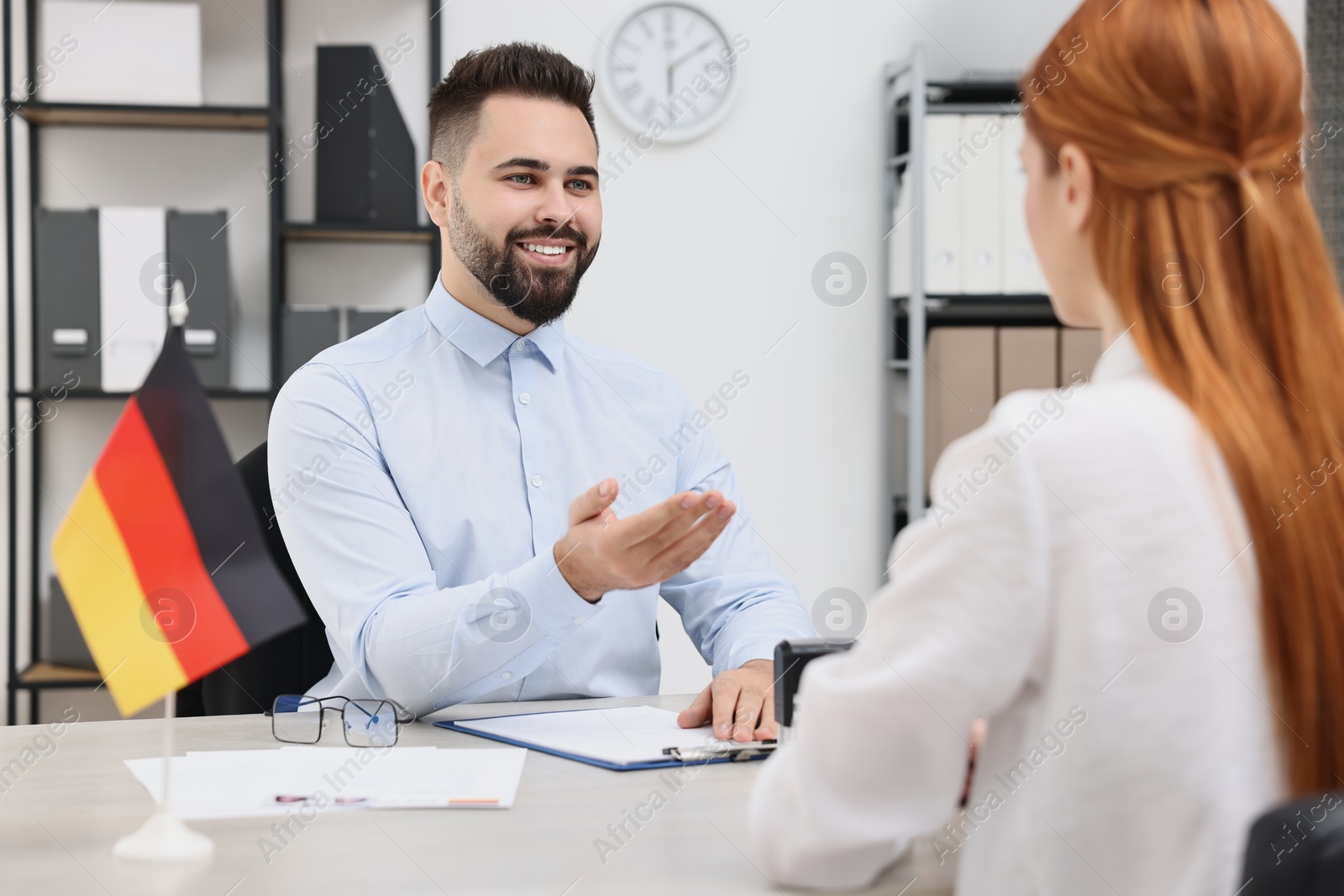 Photo of Smiling embassy worker consulting woman about immigration to Germany in office