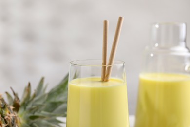 Photo of Tasty pineapple smoothie and fruit on table, closeup. Space for text