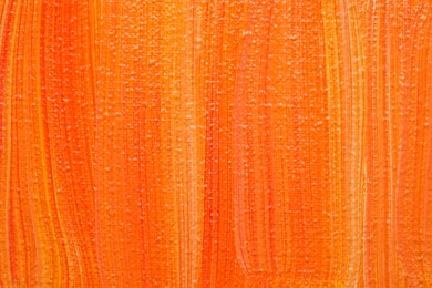 Photo of Beautiful strokes of orange oil paints as background, closeup