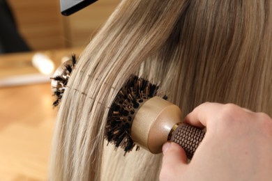 Photo of Hairdresser blow drying client's hair in salon, closeup