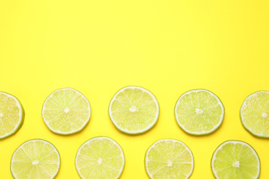 Photo of Fresh juicy lime slices on yellow background, flat lay. Space for text