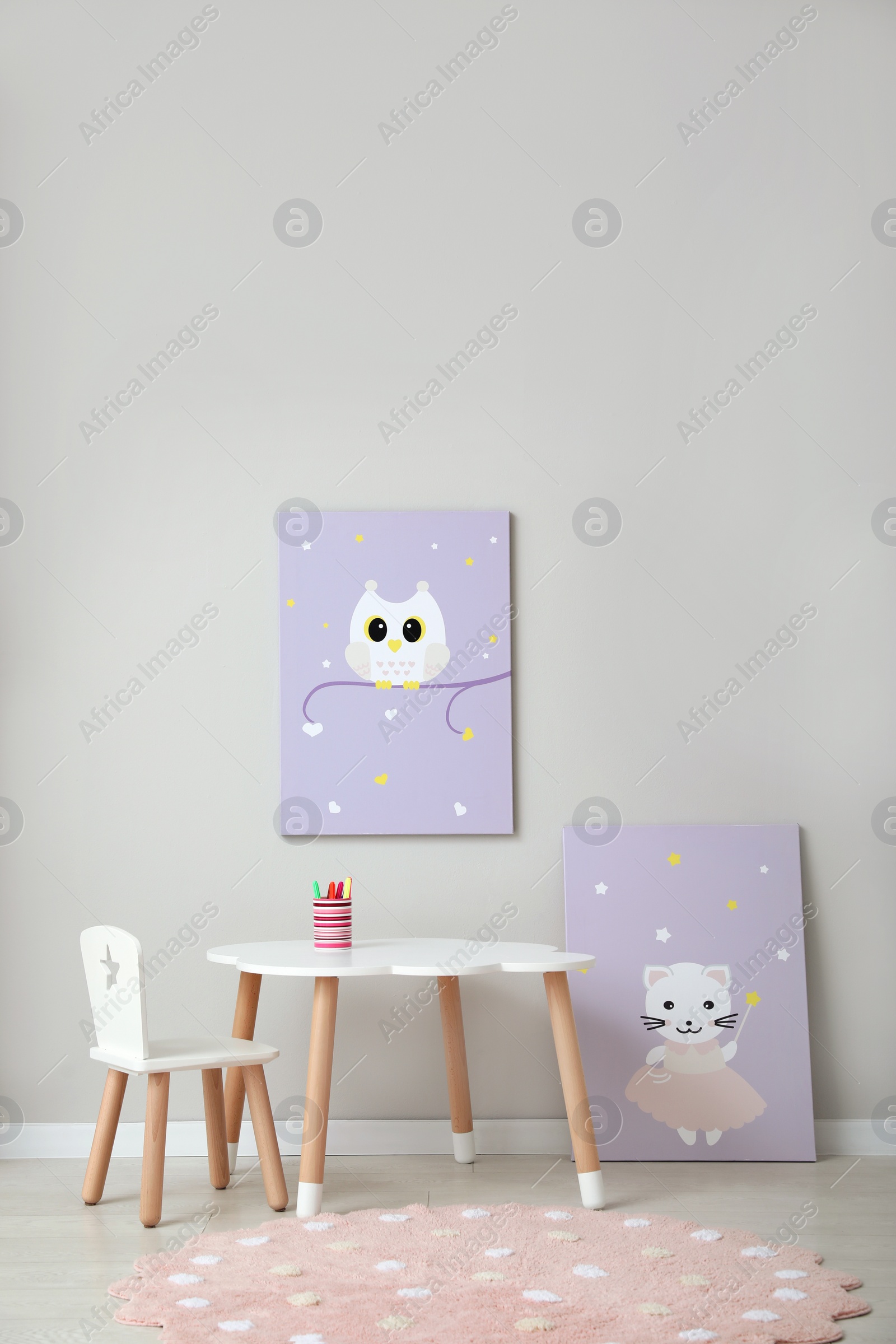 Photo of Children's room interior with table, cute paintings and empty wall. Space for design