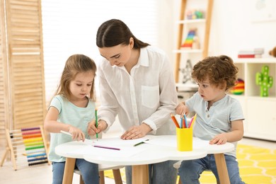 Mother and her little children drawing with colorful pencils at home