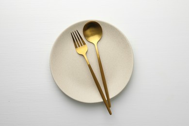 Photo of Clean plate, fork and spoon on white table, top view
