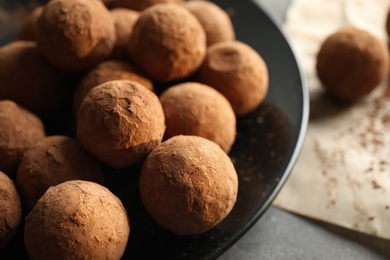 Photo of Plate with chocolate truffles on grey table, closeup