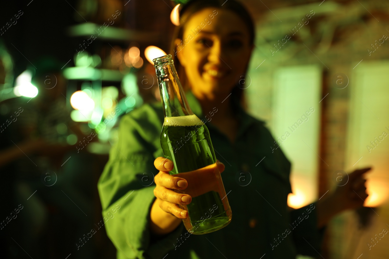 Photo of Woman with beer celebrating St Patrick's day in pub, focus on hand